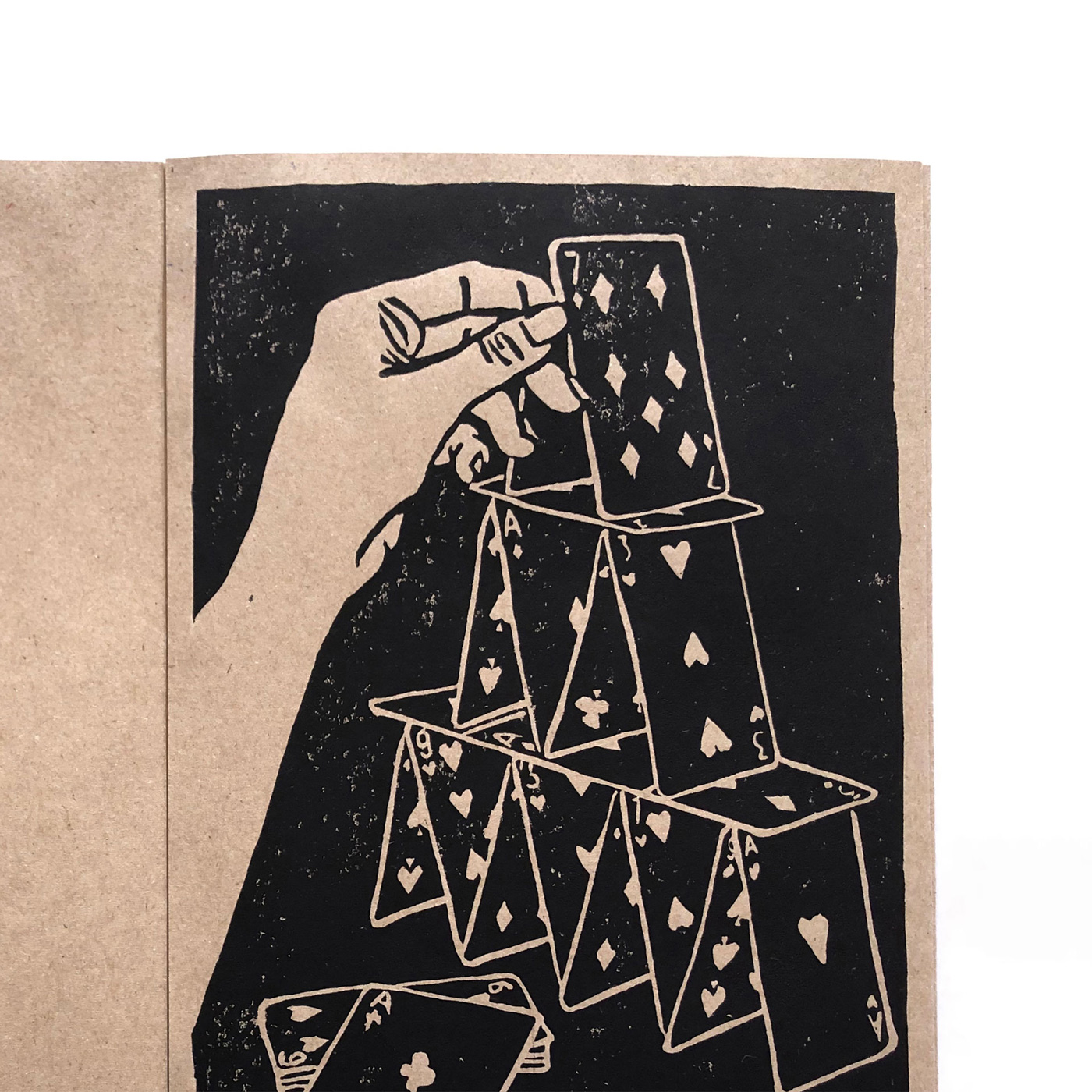 detail of a linocut printed illustration with a hand building a card house