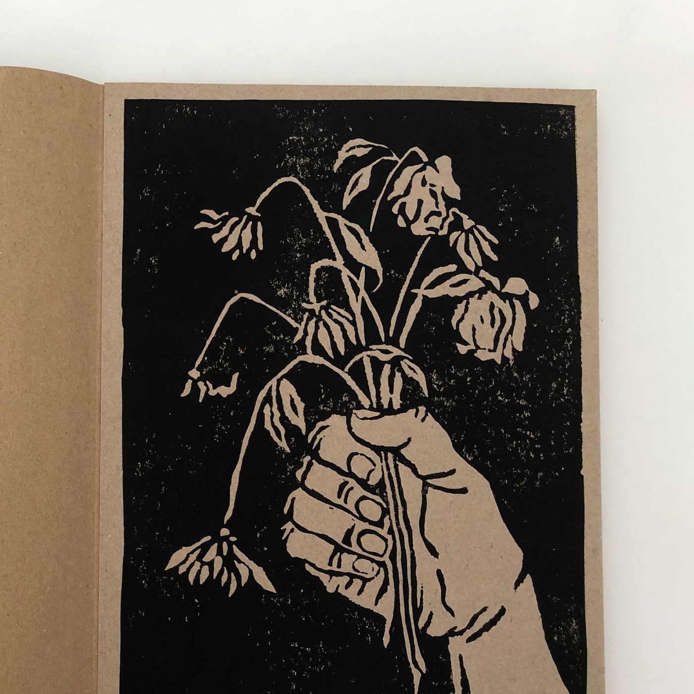 detail of a linocut printed illustration with a hand holding a bunch of wither flowers
